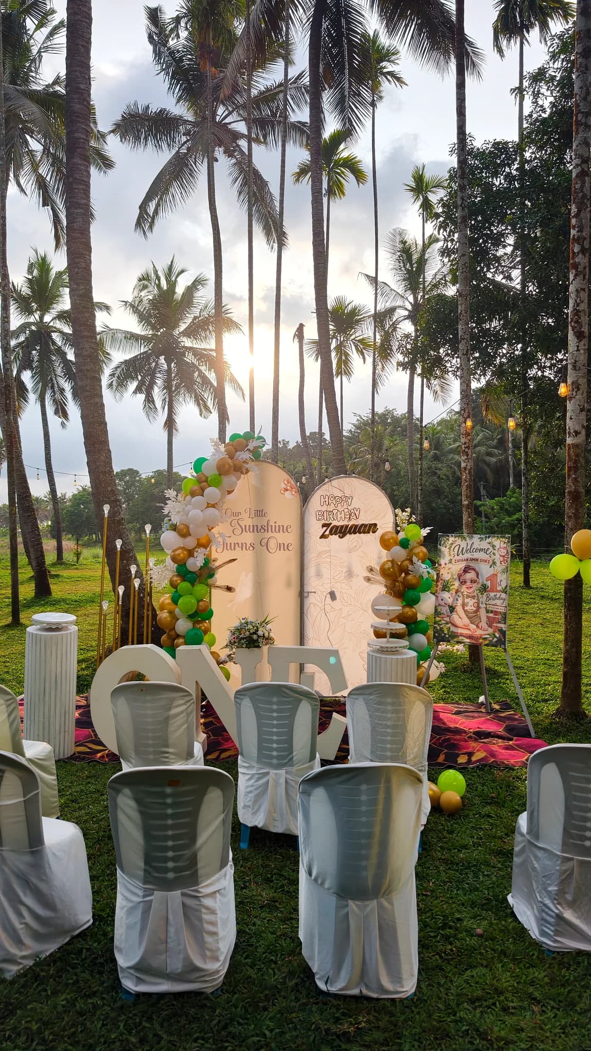 Outdoor birthday party backdrop and seating beneath coconut palms at Terrabithia in Thrissur